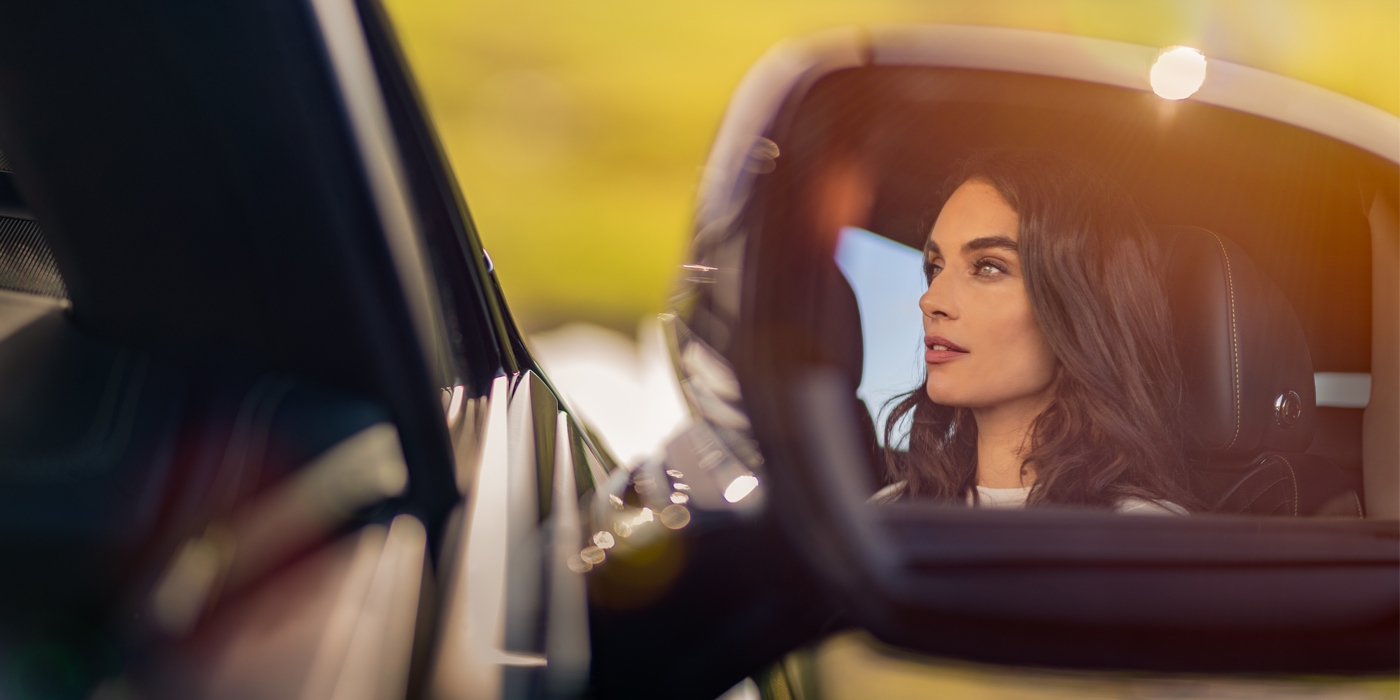 Bentley Santiago profile of dark haired woman's face in mirror of Bentley car in sunlight