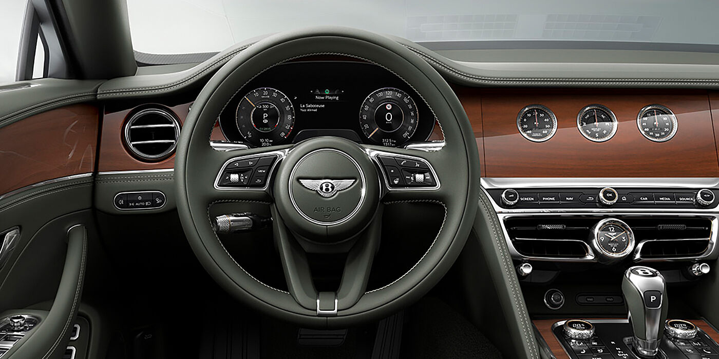 Bentley Santiago New Bentley Flying Spur sedan front cabin in Cumbrian Green hide and Crown Cut walnut veneer showing steering wheel and Rotating Display with three clocks on face