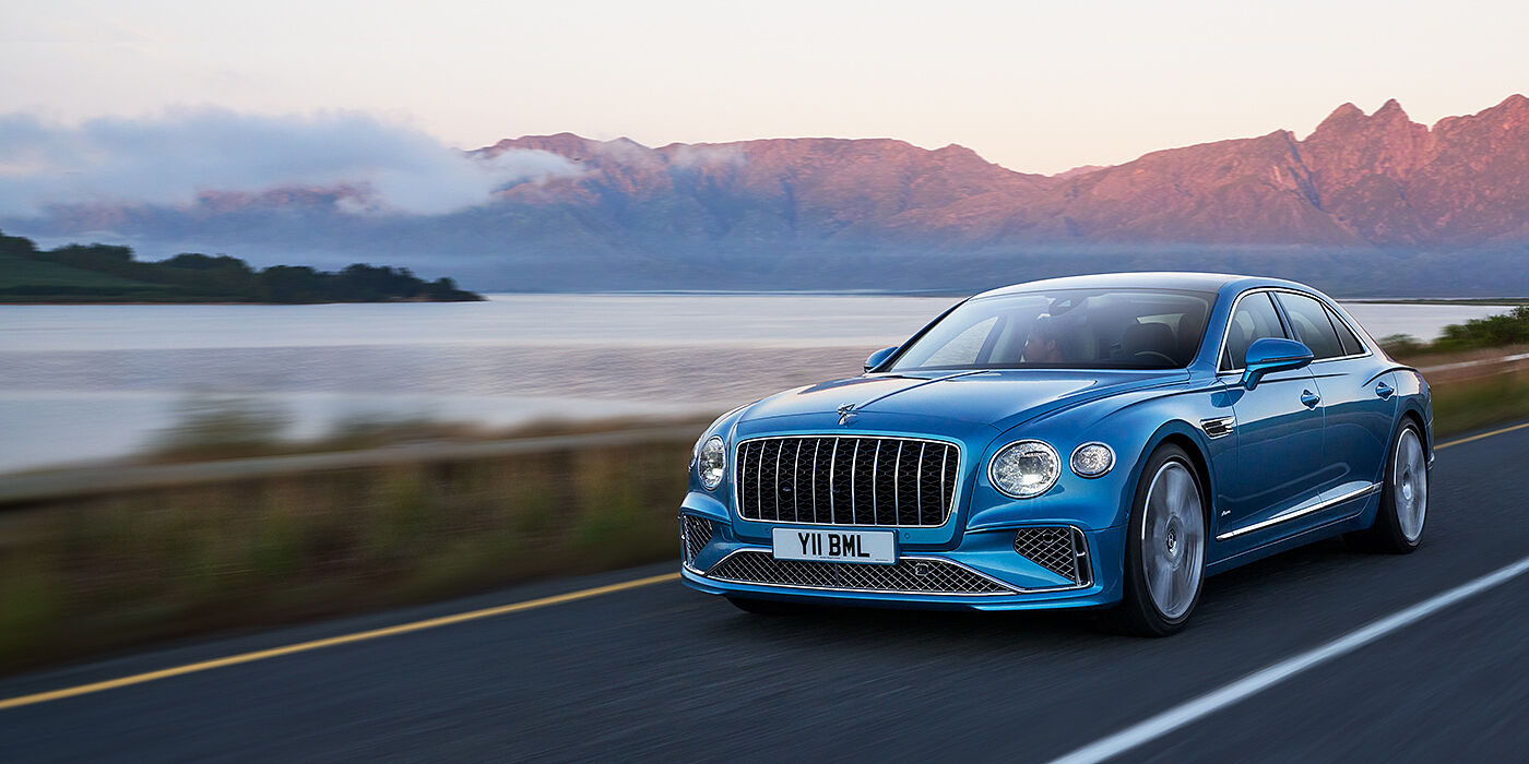 Bentley Santiago New Bentley Flying Spur Azure sedan in Light windsor blue paint by Mulliner, with 22 inch Azure wheels and chrome straight vaned grille driving on a mountain road