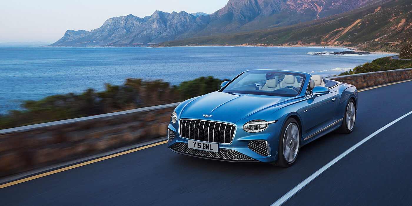 Bentley Santiago New Bentley Continental GTC Azure convertible in Light Windsor blue paint with 22 inch Azure wheels and chrome grill, driving dynamically by the sea