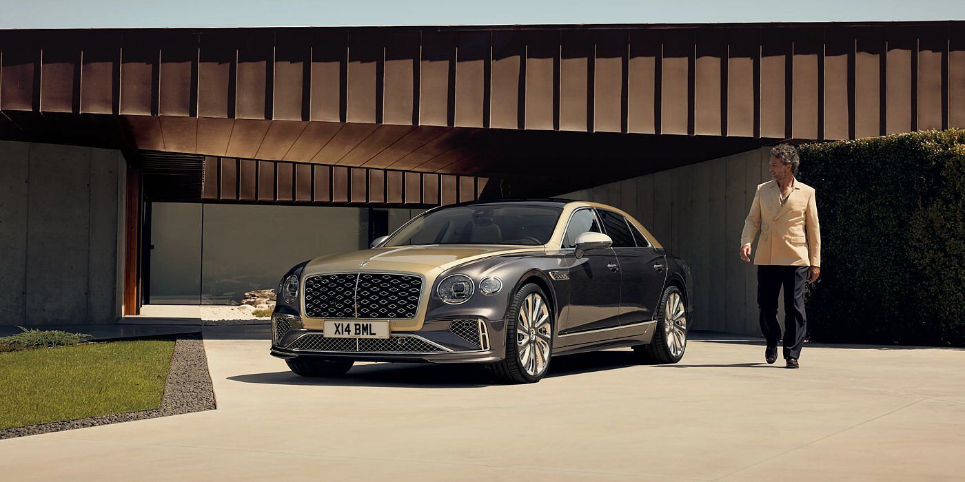 Bentley Santiago Bentley New Flying Spur Mulliner V8 hybrid sedan front three quarters in Rose Gold over Magnetic paint, parked near modern home