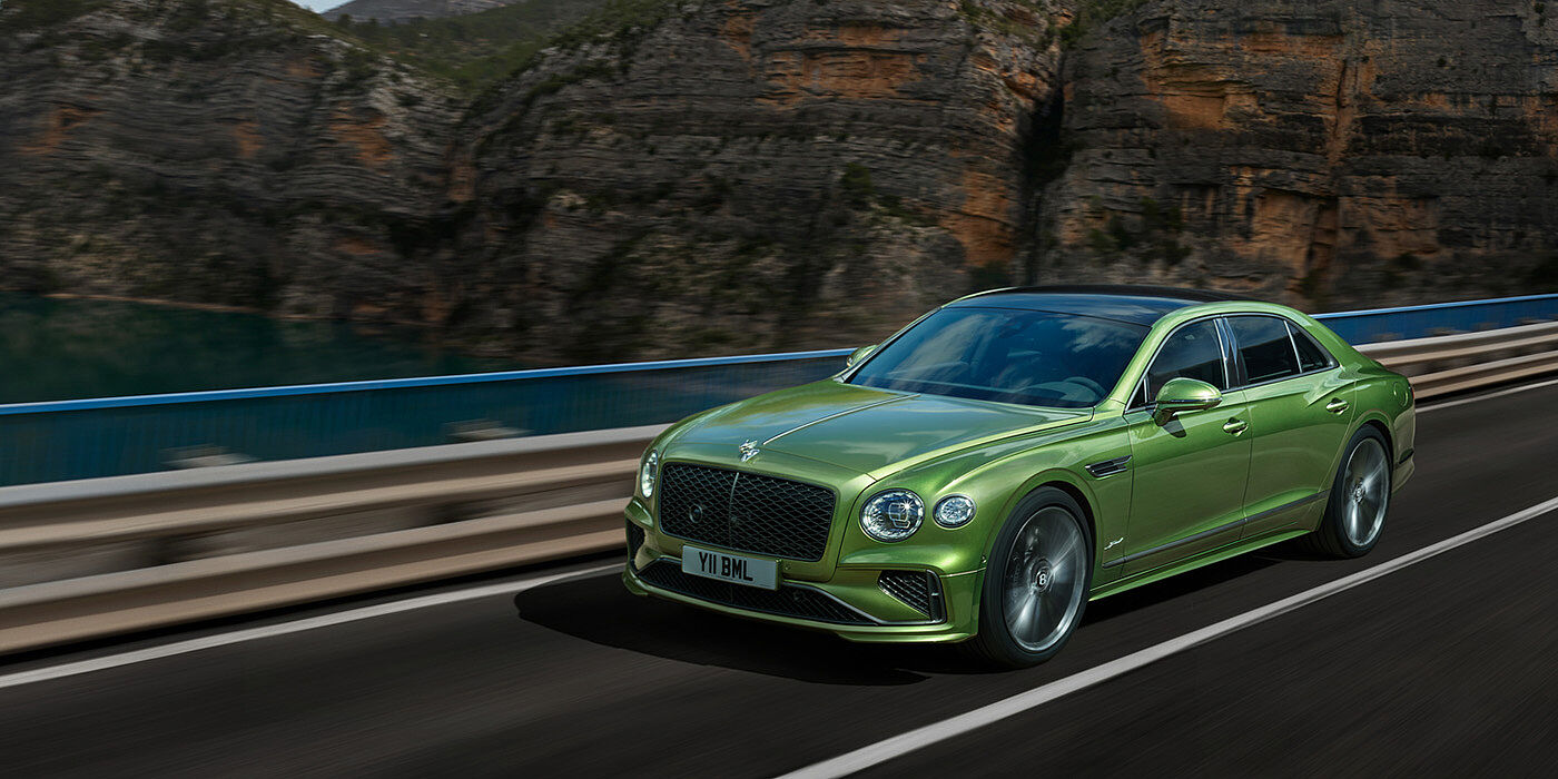 Bentley Santiago Bentley New Flying Spur Speed v8 hybrid sedan driving dynamically on a mountain road in Tourmaline Green paint
