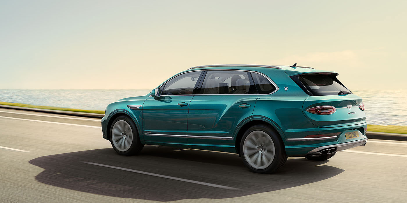 Bentley Santiago Bentley Bentayga Extended Wheelbase Azure luxury SUV rear three quarter in Topaz Blue by Mulliner paint, driving on an ocean road.
