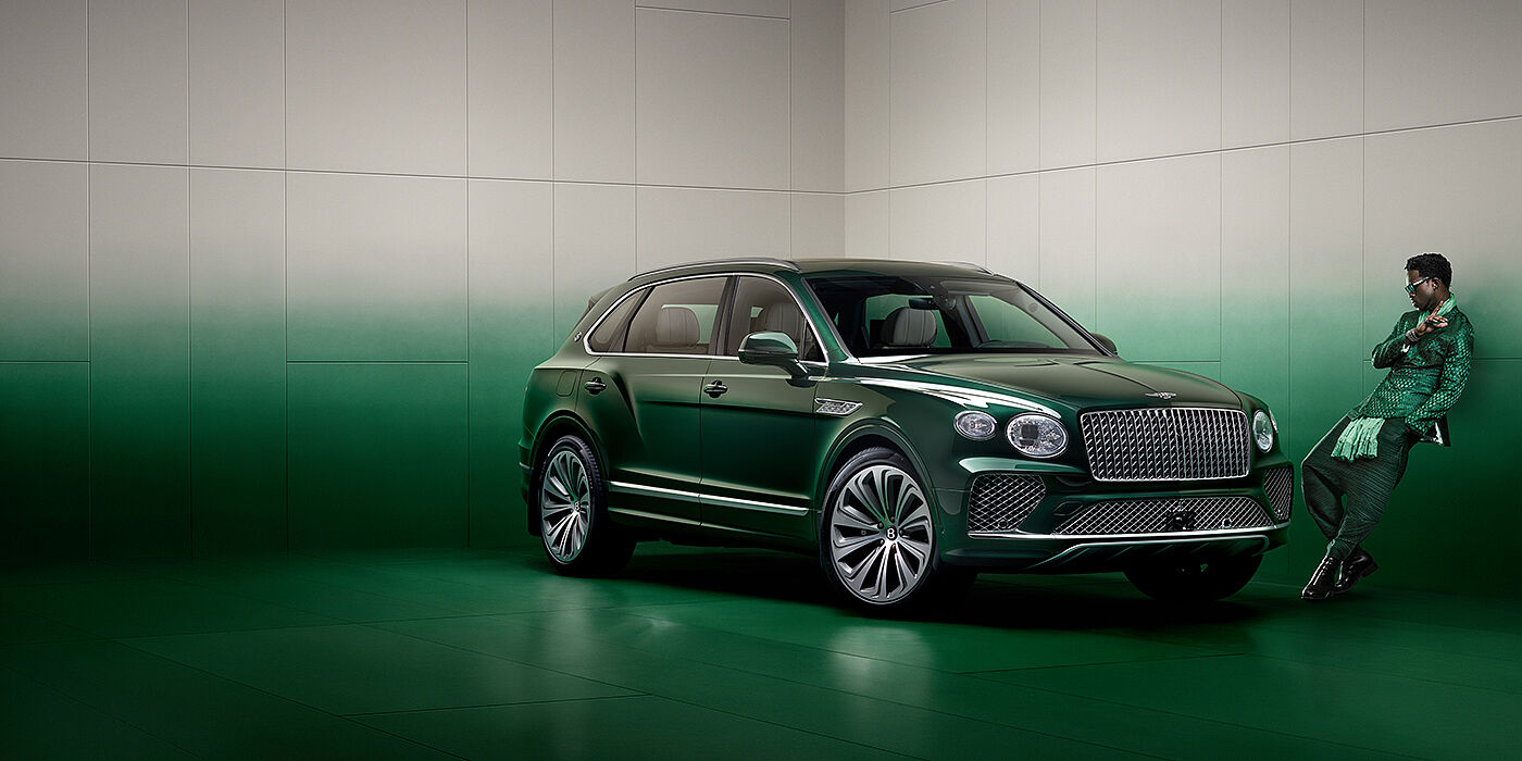 Bentley Santiago Wisdom K leans against wall next to Bentley Bentayga Extended Wheelbase Atelier Edition SUV in Light Emerald green paint