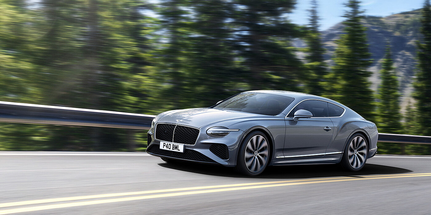 Bentley Santiago New Bentley Continental GT coupe in Silverlake paint and 22 inch ten-spoke wheels, driving dynamically on a tree-lined road in the sunshine