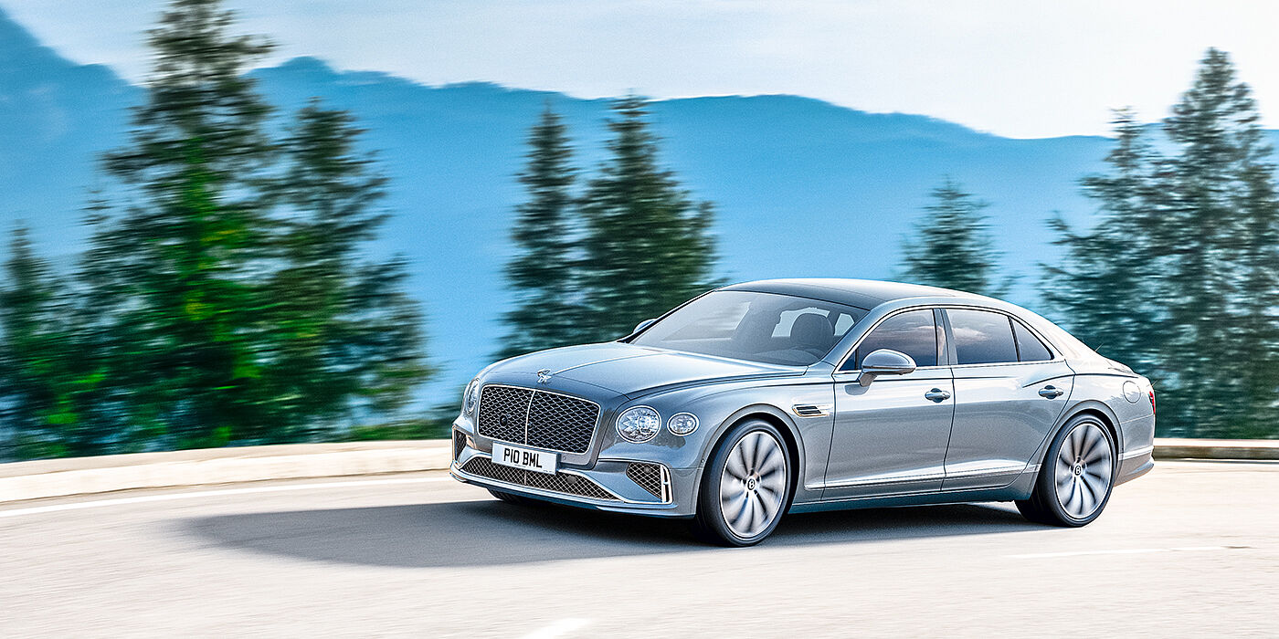 Bentley Santiago New Bentley Flying Spur sedan side view in Silverlake paint with ten spoke wheels and chrome matrix grille driving dynamically on a mountain road