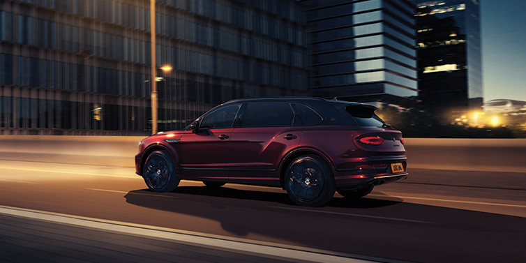 Bentley Santiago Bentley Bentayga Extended Wheelbase Mulliner SUV in Cricket Ball red paint driving dynamically in city at night